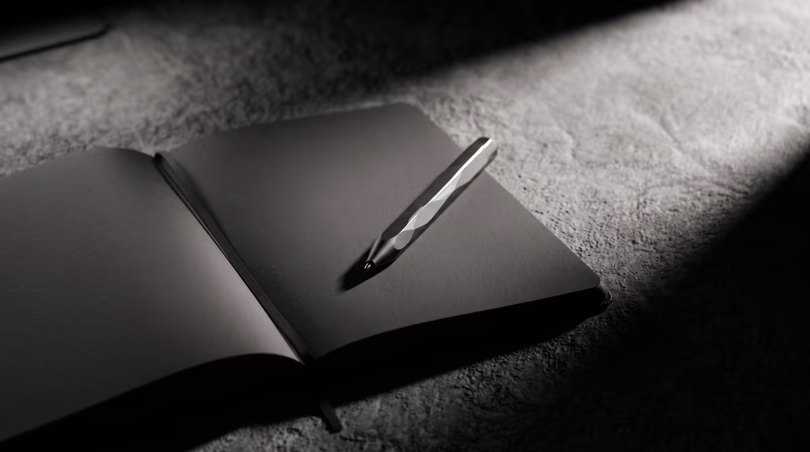 A stylus resting on a black sketchbook